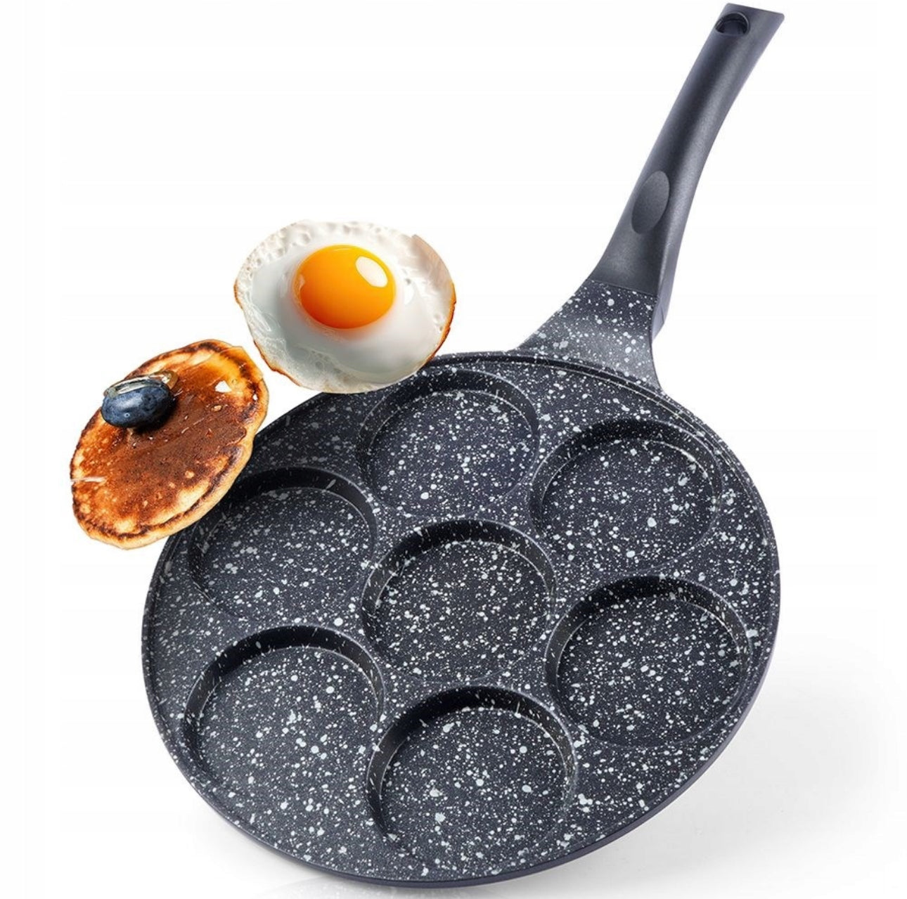 Non-stick stekepanne med håndtak og stekt egg og pannekake over hulldelt overflate