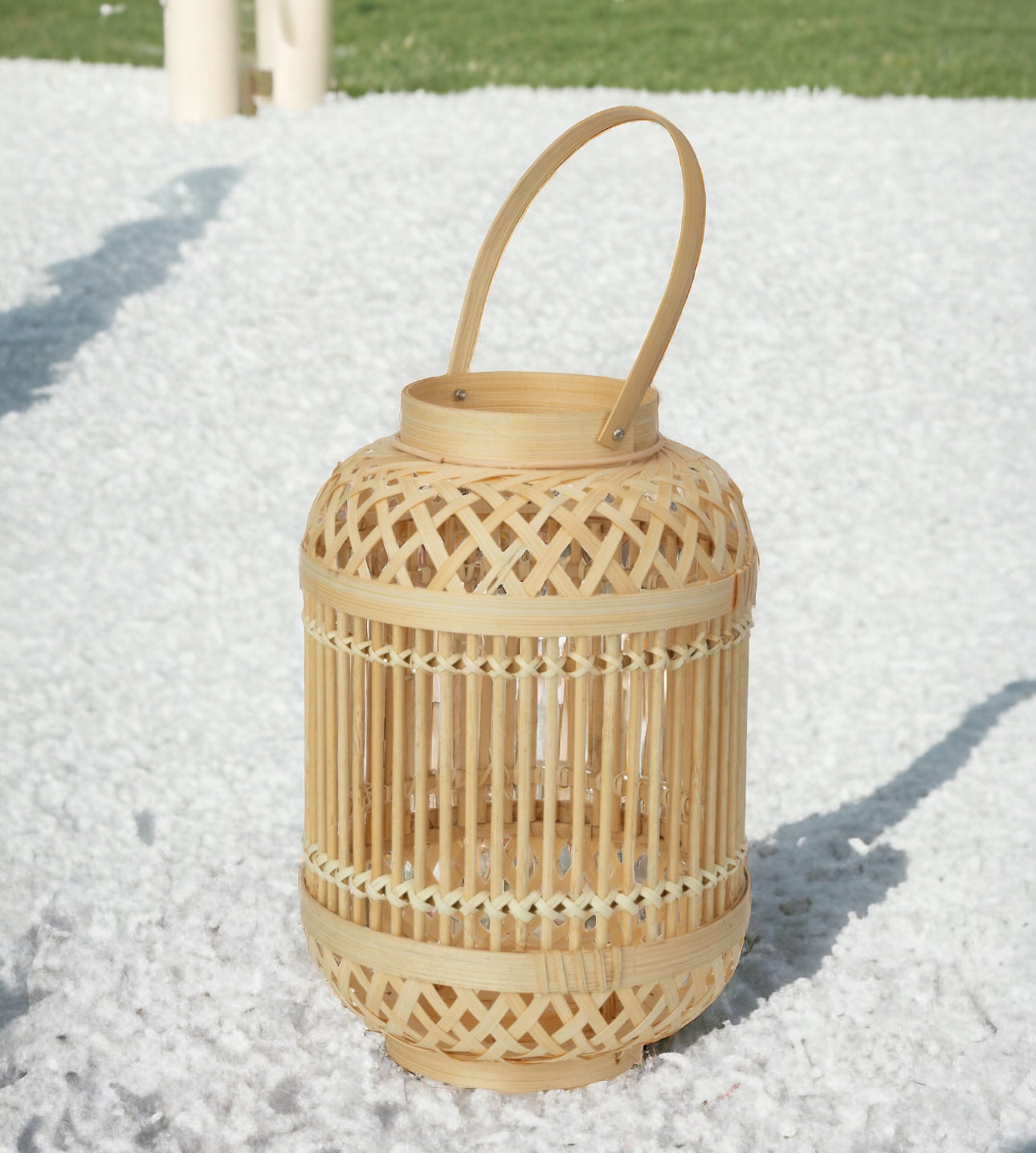 Bambuslykt med håndtak plassert på hvit grus i solrik hageatmosfære