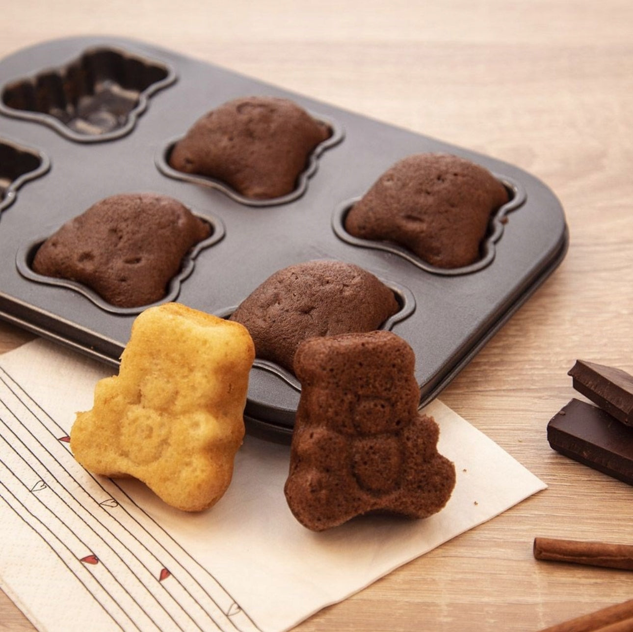 To ferdigstekte muffins i bjørneform foran bakeform med flere sjokoladekaker