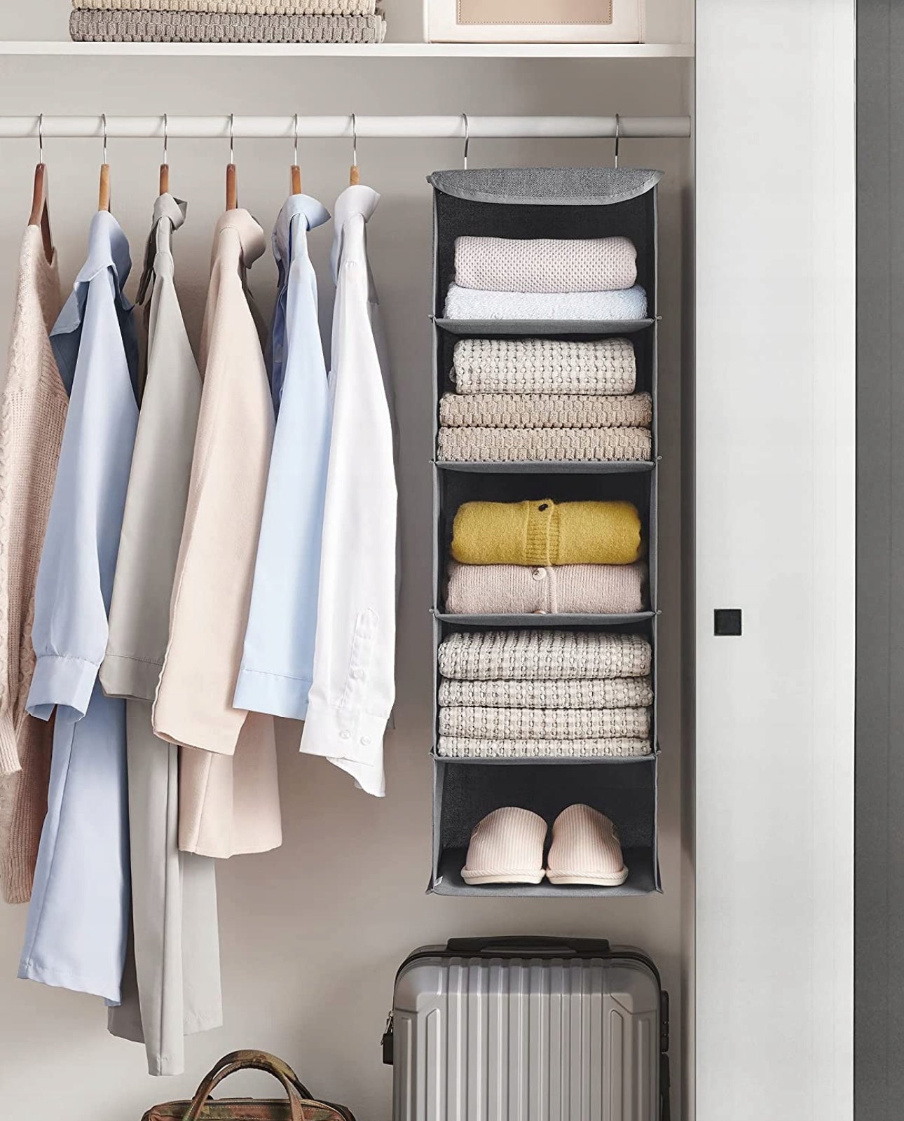 Garderobe med hengende oppbevaringssystem i grå tekstil fylt med klær og tøfler