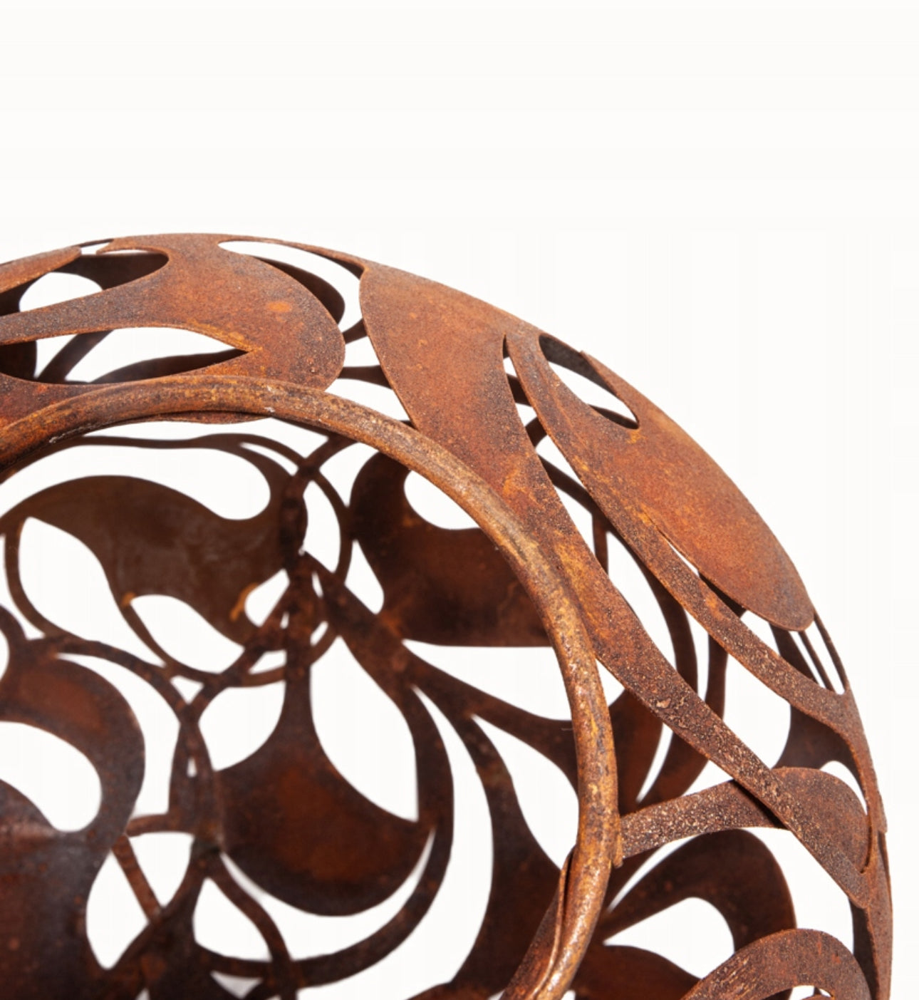 Nærbilde av mønstre i rustfarget metallkule med hul innside