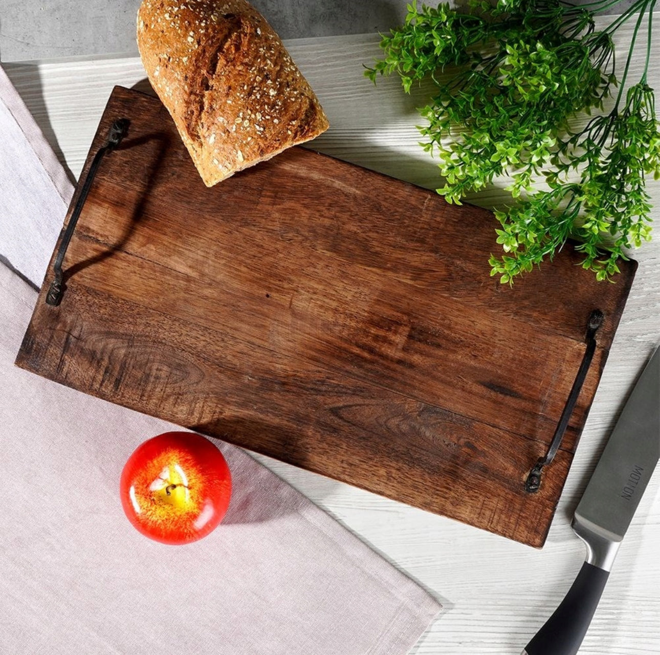 Oversiktsbilde av serveringsbrett med brød, frukt og planter på kjøkkenbord