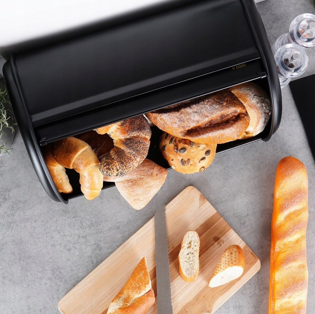 Full brødboks med croissanter og rundstykker på kjøkkenbenk med kjøkkenredskaper