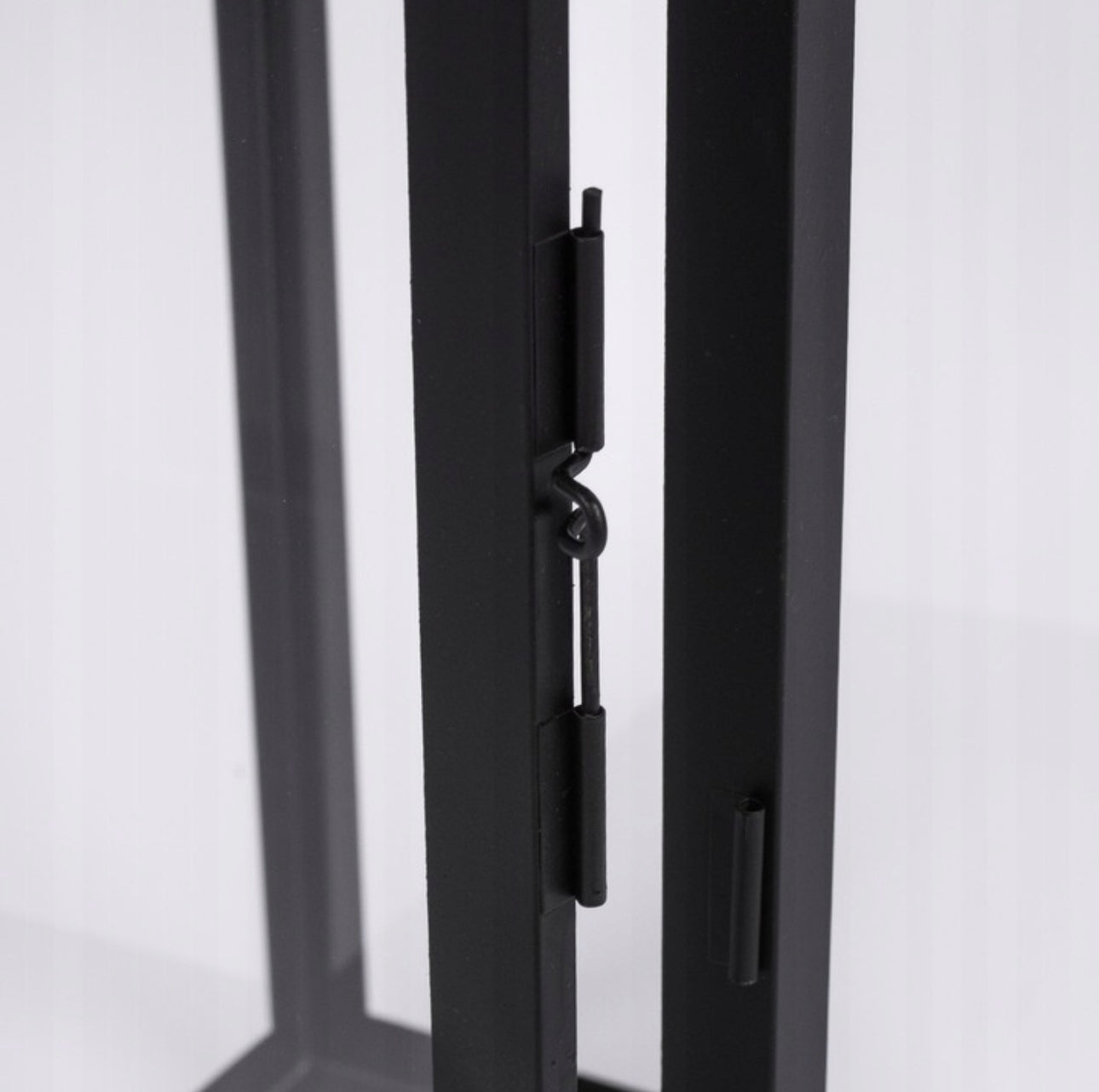 Nærbilde av lukkehake i svart metall på døråpning til lyslykt