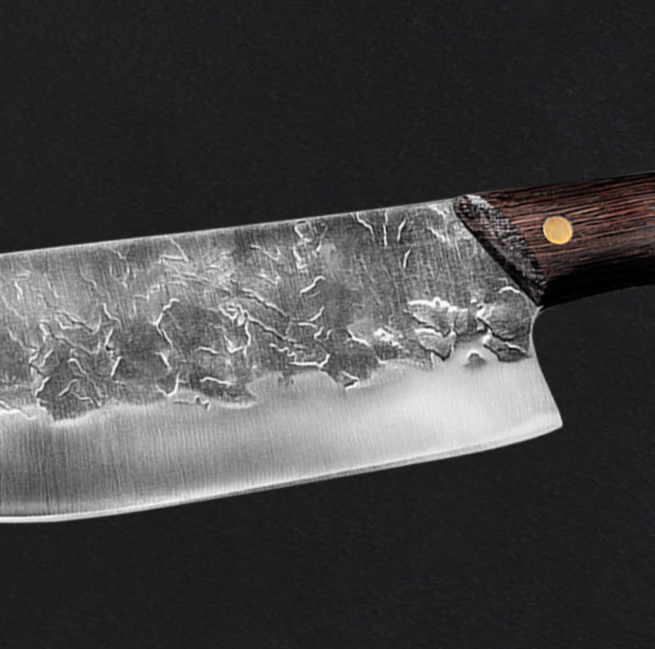 Detaljbilde av håndbanket knivblad i rustfritt stål med mørkt trehåndtak