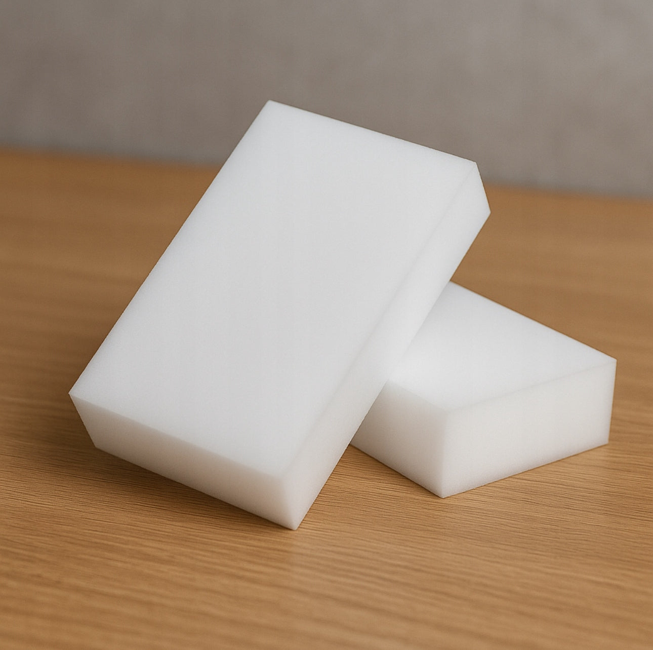 To hvite melaminsvamper liggende på treoverflate i minimalistisk stil