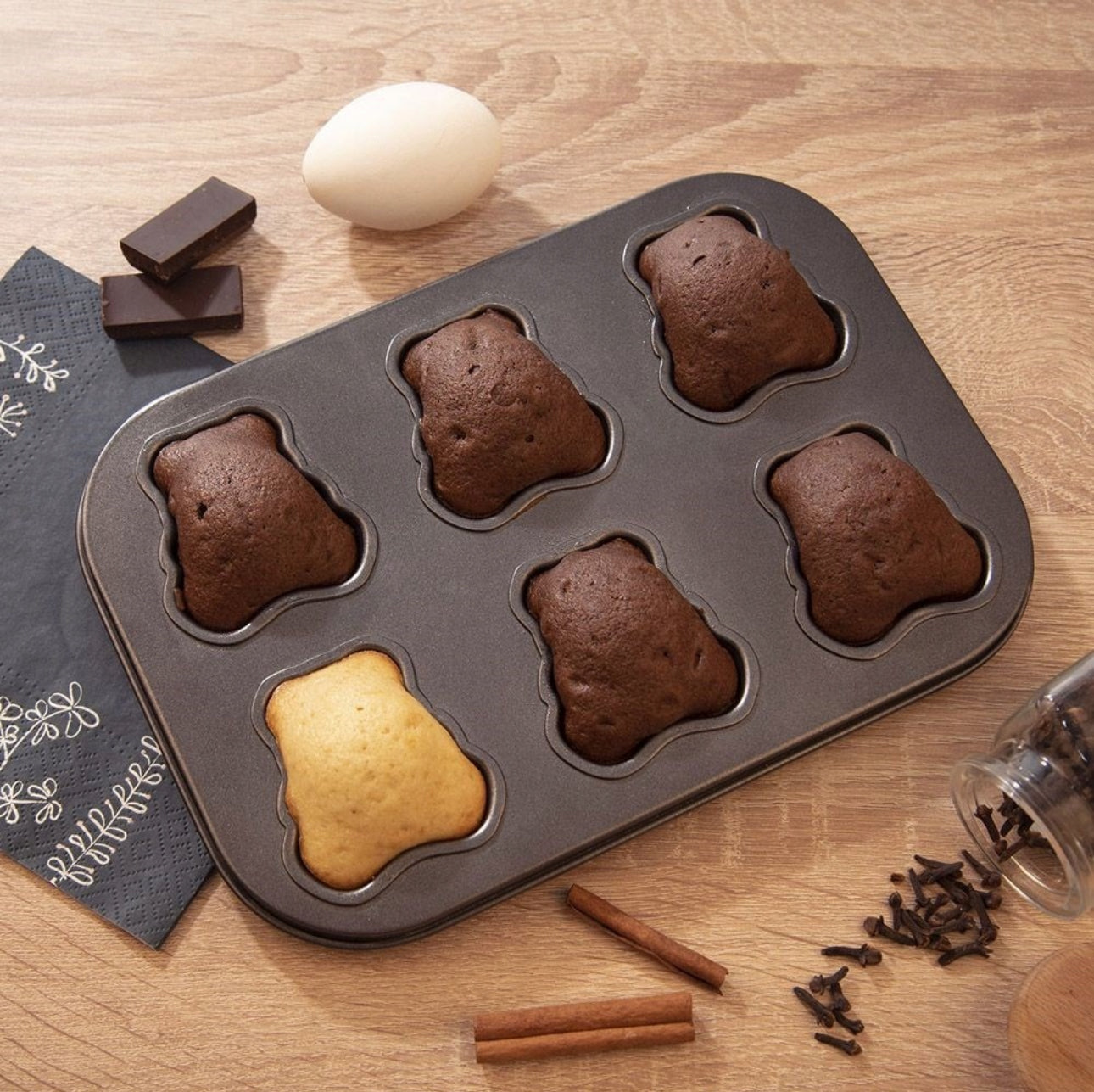 Ferdig stekte muffins i bjørneformet bakeform på kjøkkenbenk med egg og sjokolade