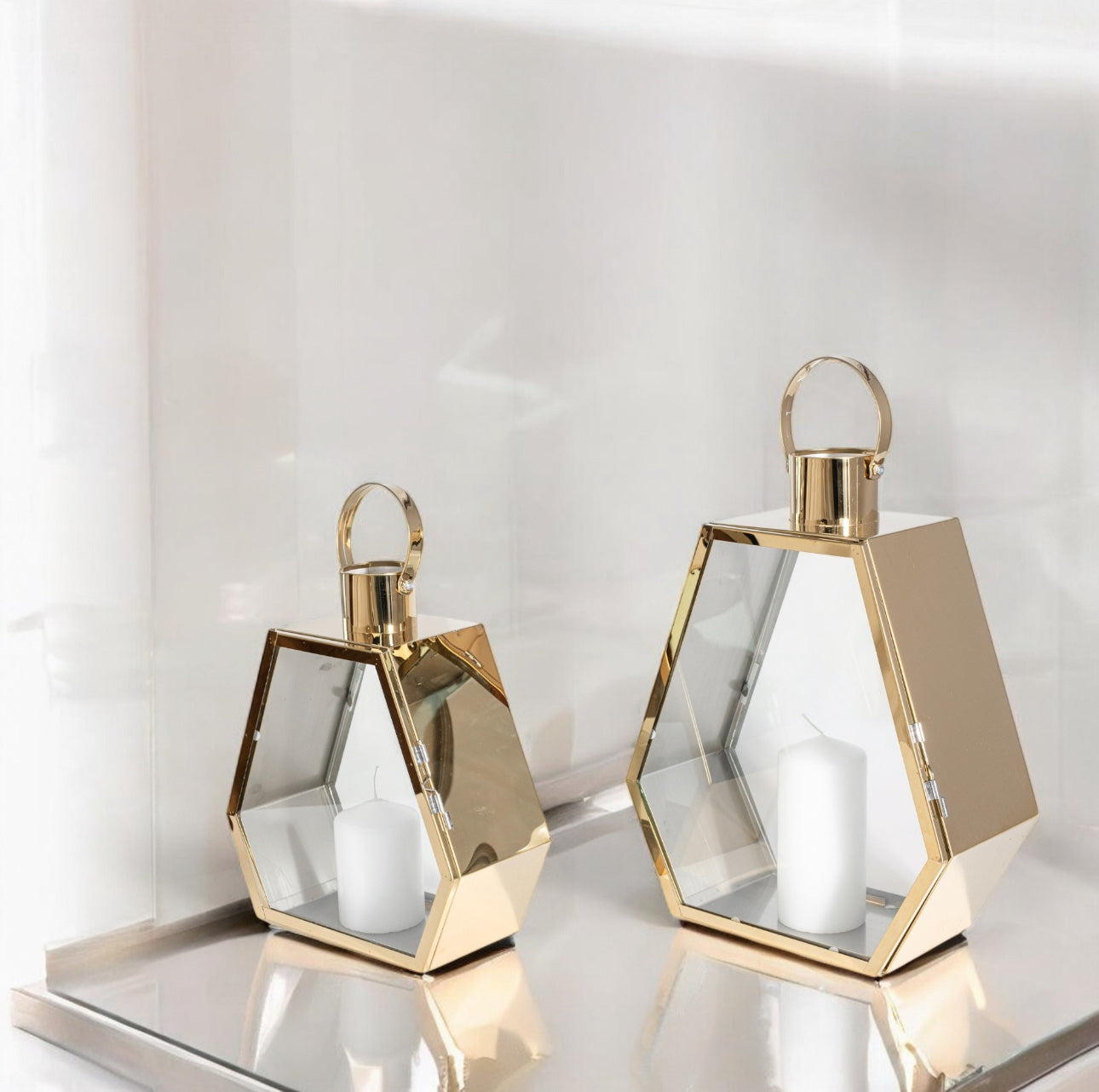 Sett med to gullfargede metalllykter med lys, plassert på speiloverflate i lyst interiør