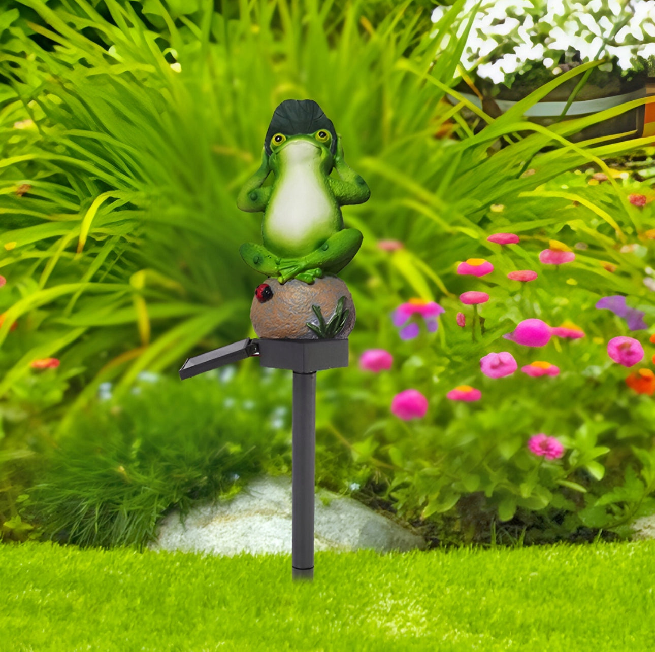 Dekorativ frosk med solcellelys plassert i blomsterbed i hage