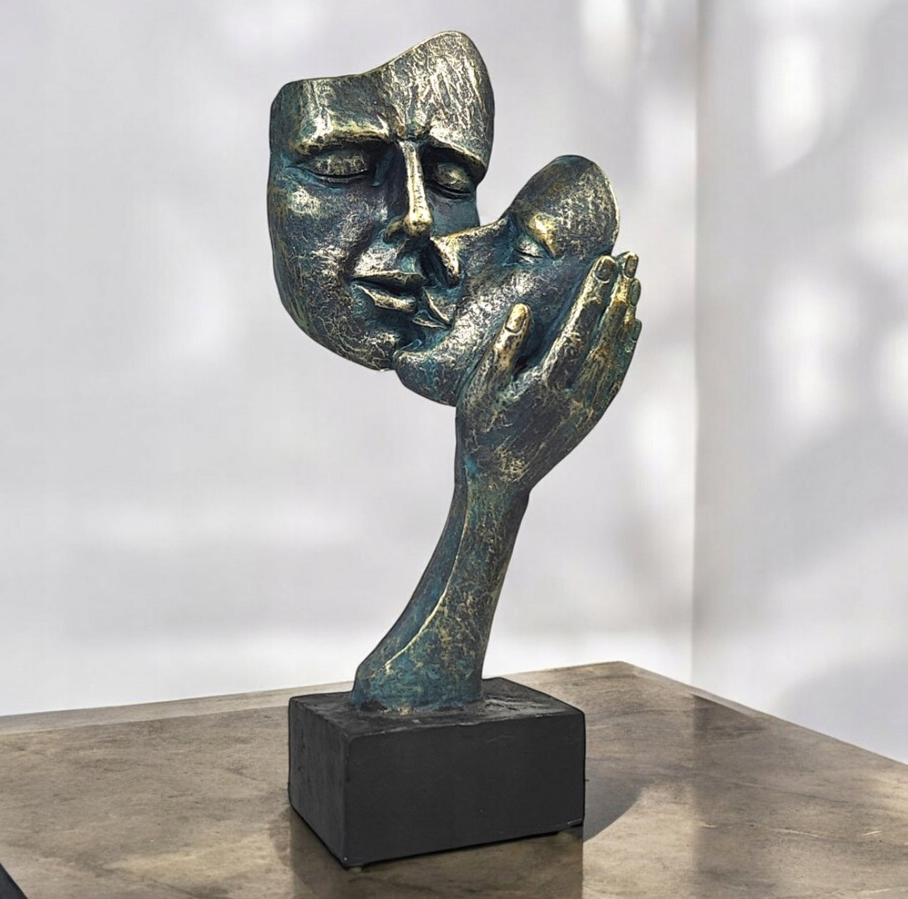 Moderne kunstskulptur i bronsefinish med to ansikter på mørk bordplate