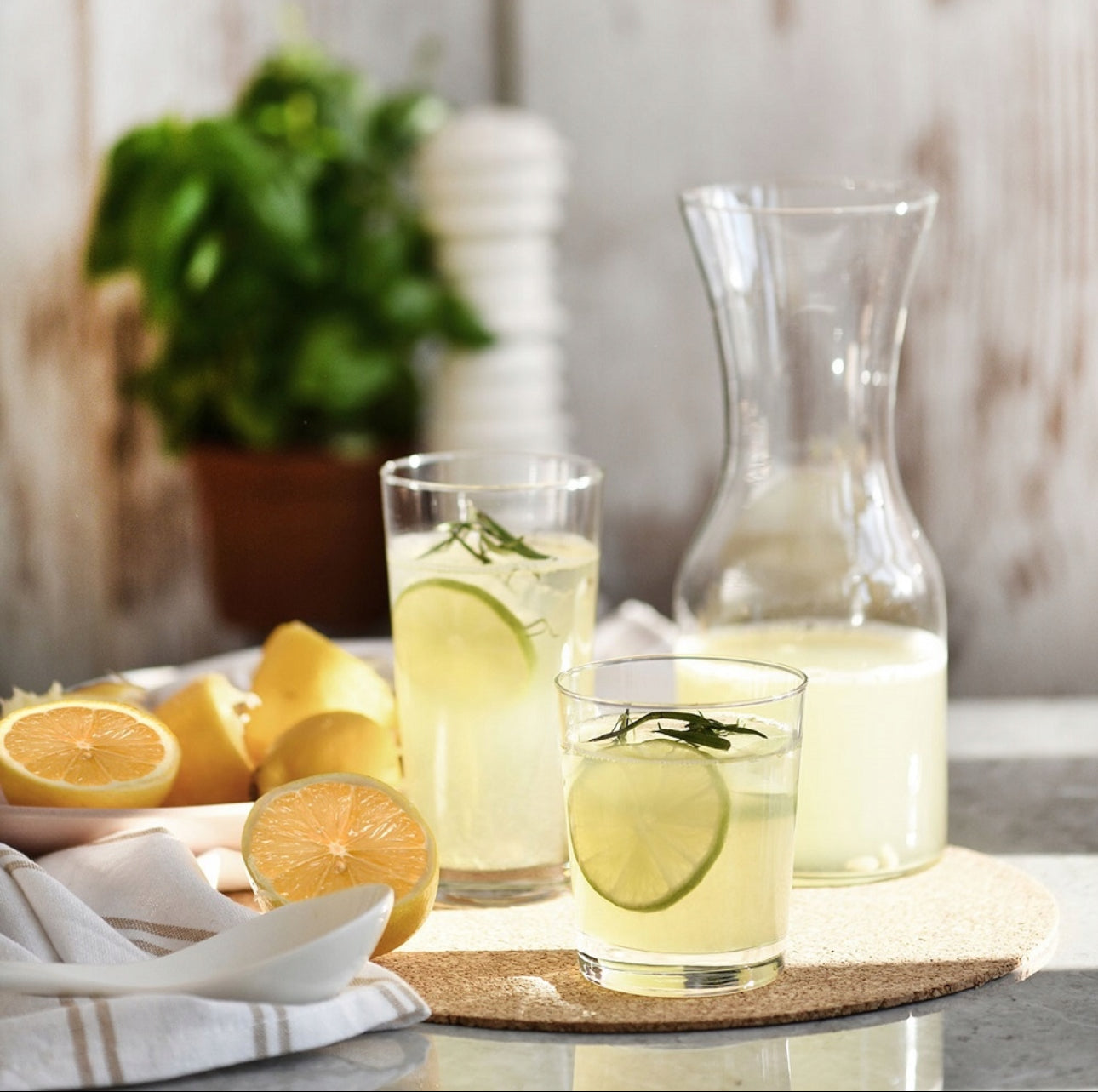 Glasskaraffel med lemonade, sitroner og glass på borddekorasjon