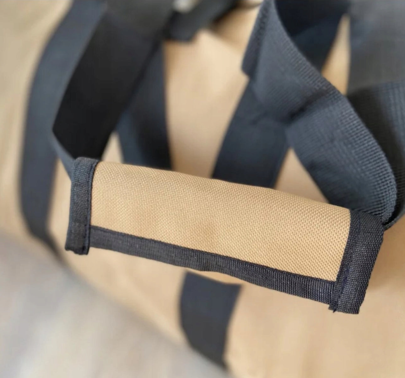 Nærbilde av polstret håndtak på beige vedbag i slitesterkt lerret