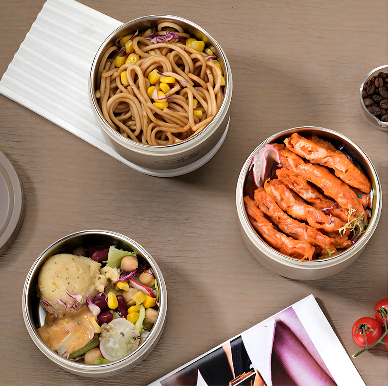 Åpne bento-bokser med varm mat som pasta, salat og kylling, sett ovenfra