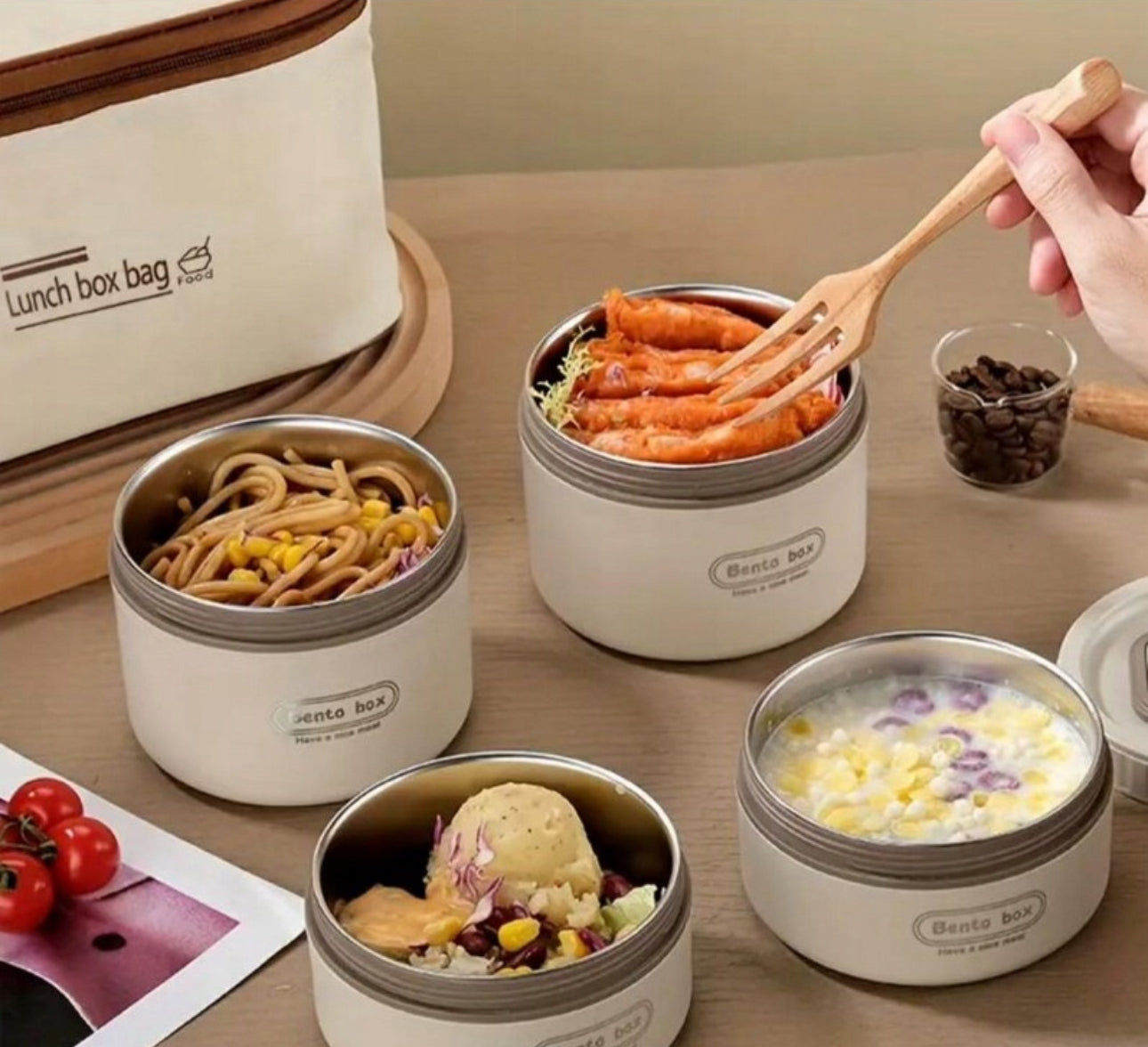 Bento-bokser fylt med variert lunsj, hånd med tregaffel og termobag i bakgrunnen