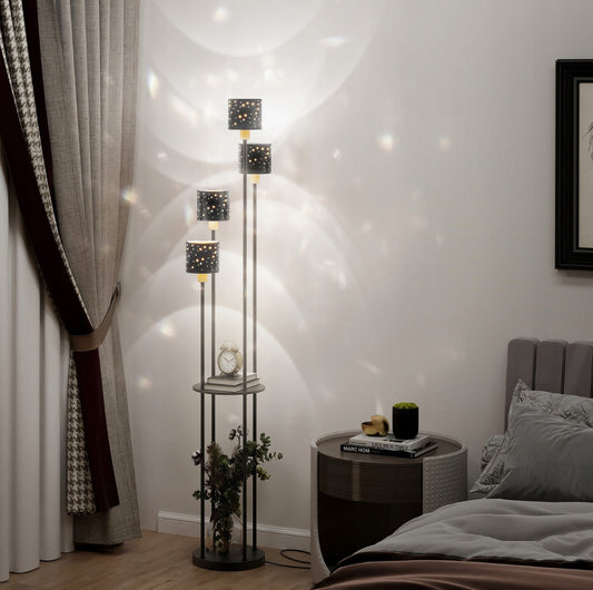 Svart gulvlampe med fire skjermer og gull innside ved sengegavl