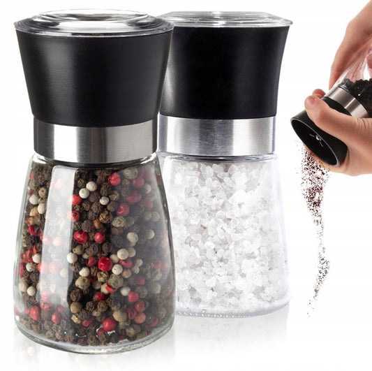 To manuelle salt- og pepperkverner i glass med sort topp og stålring, fylt med grovt salt og pepperkorn.