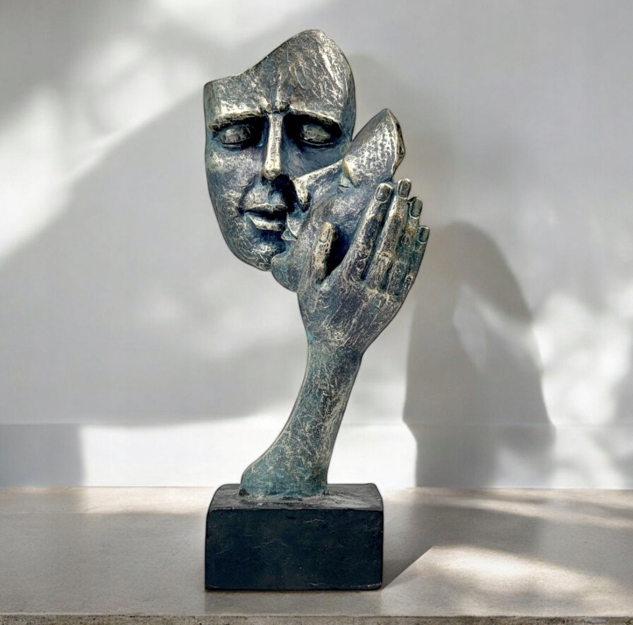 Abstrakt bronsefarget skulptur med kyssende ansikter på lys steinoverflate