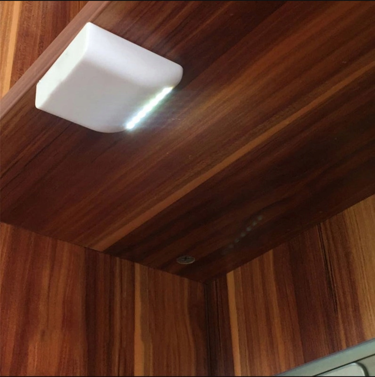 Kompakt hvit LED-lampe med kaldhvitt lys montert under trehylle
