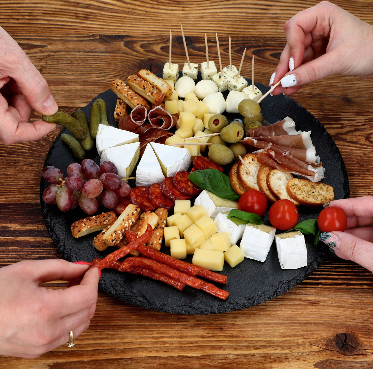 Serveringsfat med tapas og fingermat, flere hender som forsyner seg