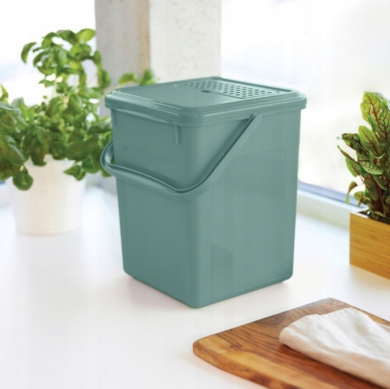 Grønn kjøkkenkompostbøtte plassert på benk ved planter, 9L