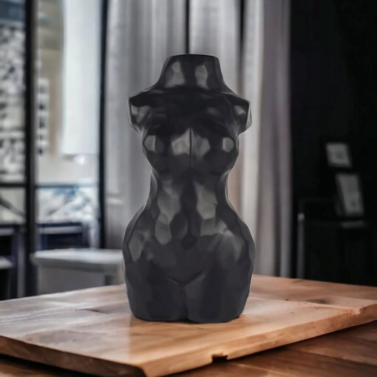 Svart skulpturell vase med fasettert overflate på stuebord