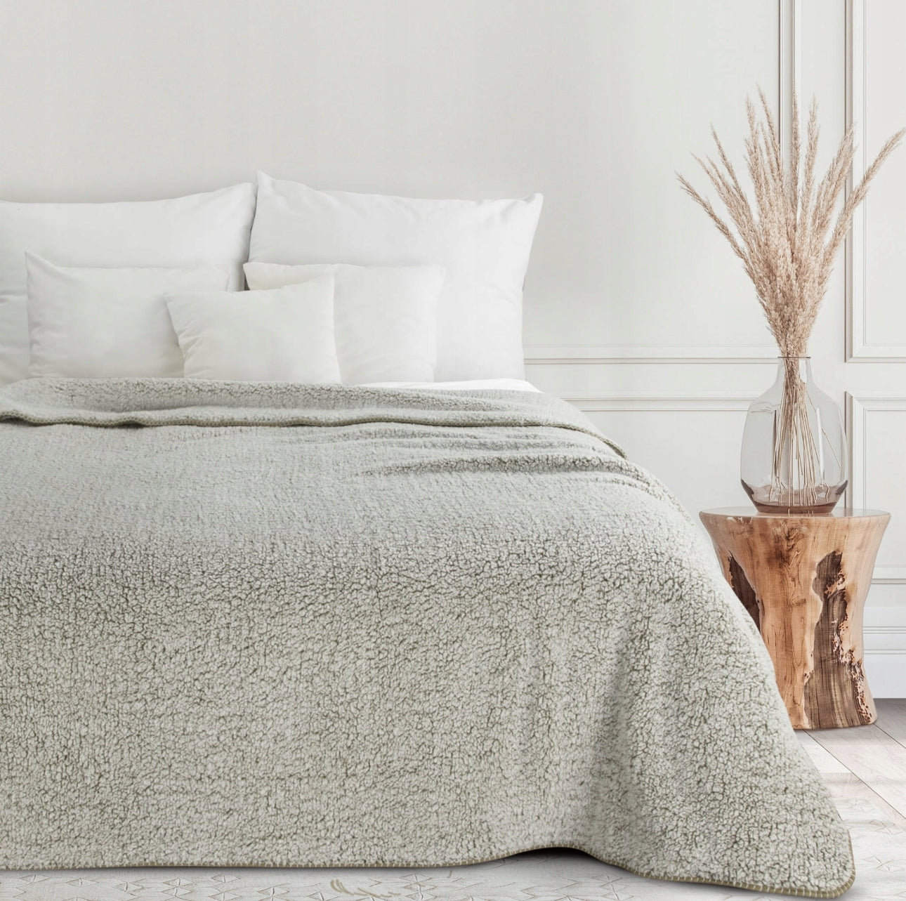 Mykt bouclé-pledd i beige toner dandert over dobbeltseng i moderne soverom