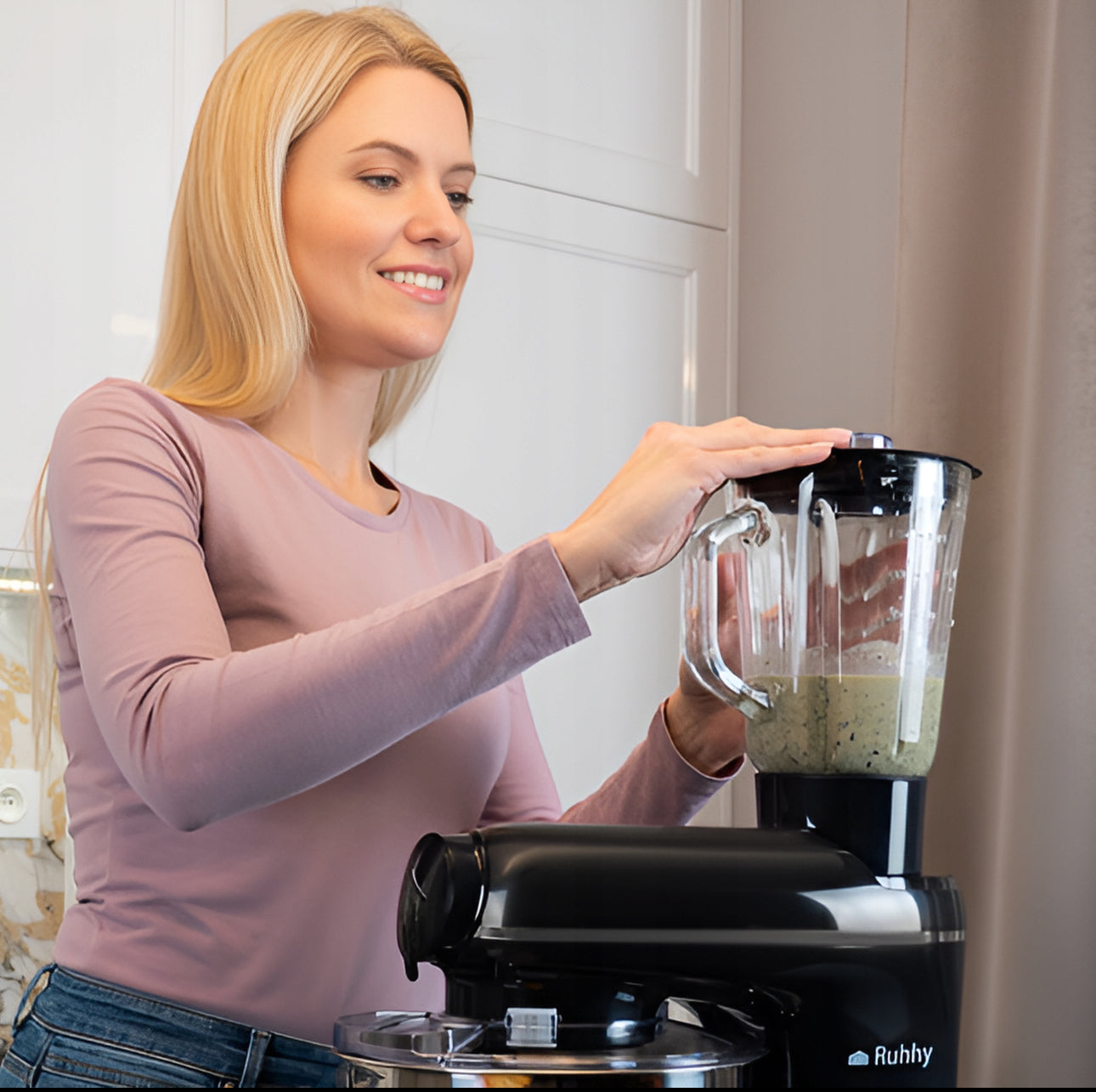 Kvinne blender grønnsaker med kjøkkenmaskin med glasskanne