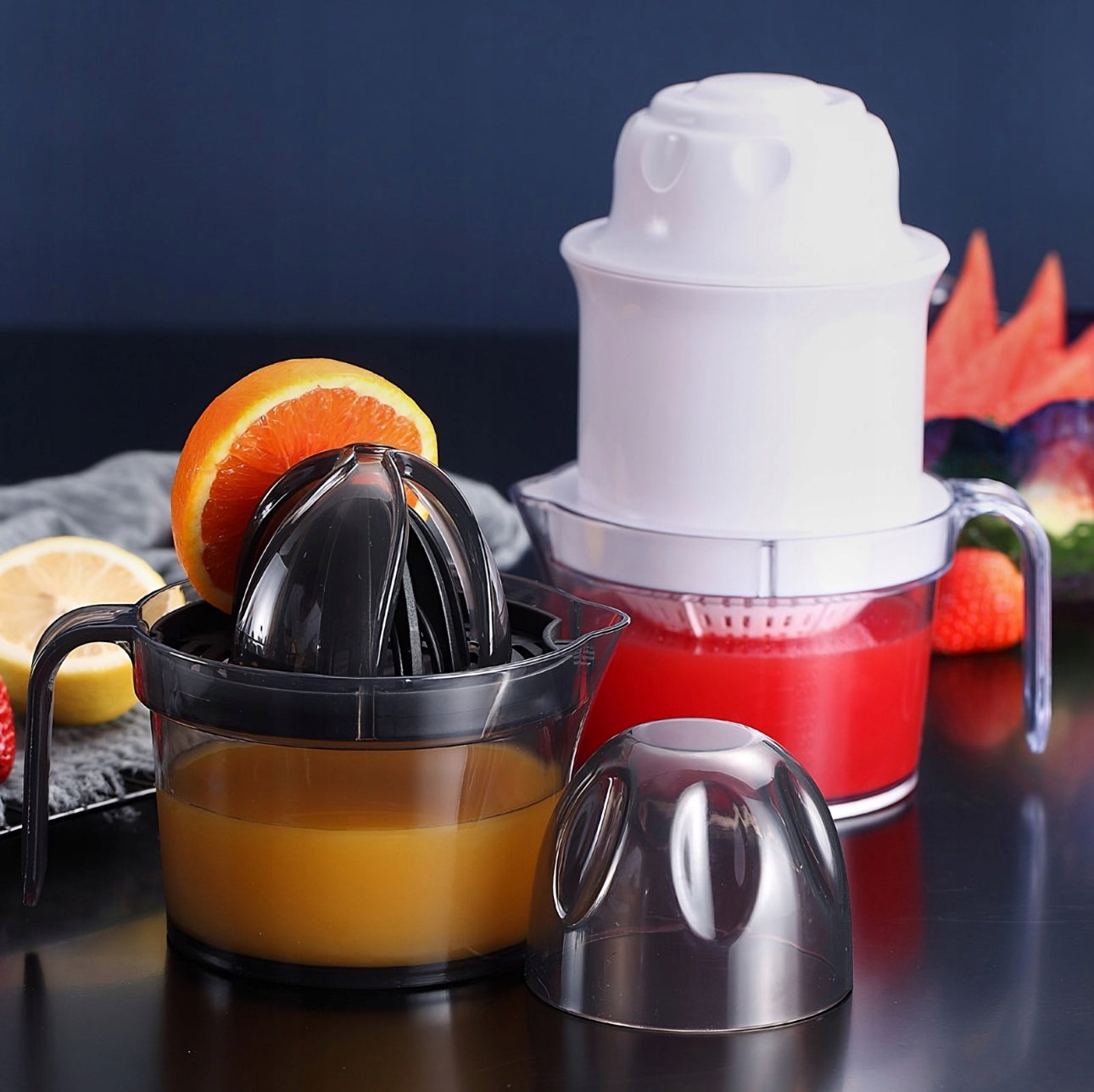 To sitruspresser – én svart og én hvit – fylt med juice og omgitt av appelsin og sitron.