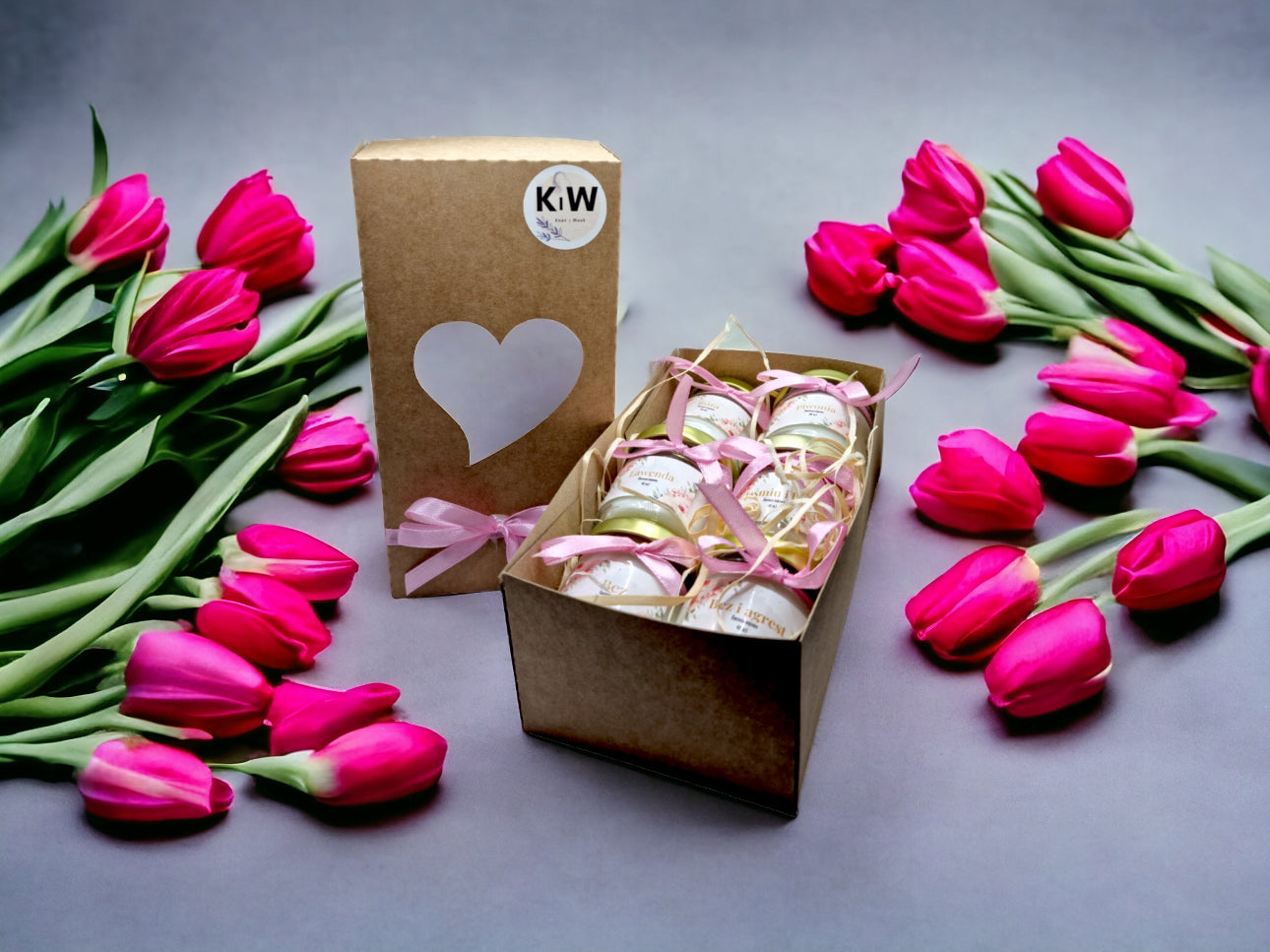Gavesett med duftlys i glass med rosa bånd og tulipaner rundt