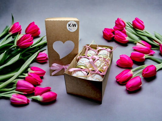 Gavesett med duftlys i glass med rosa bånd og tulipaner rundt