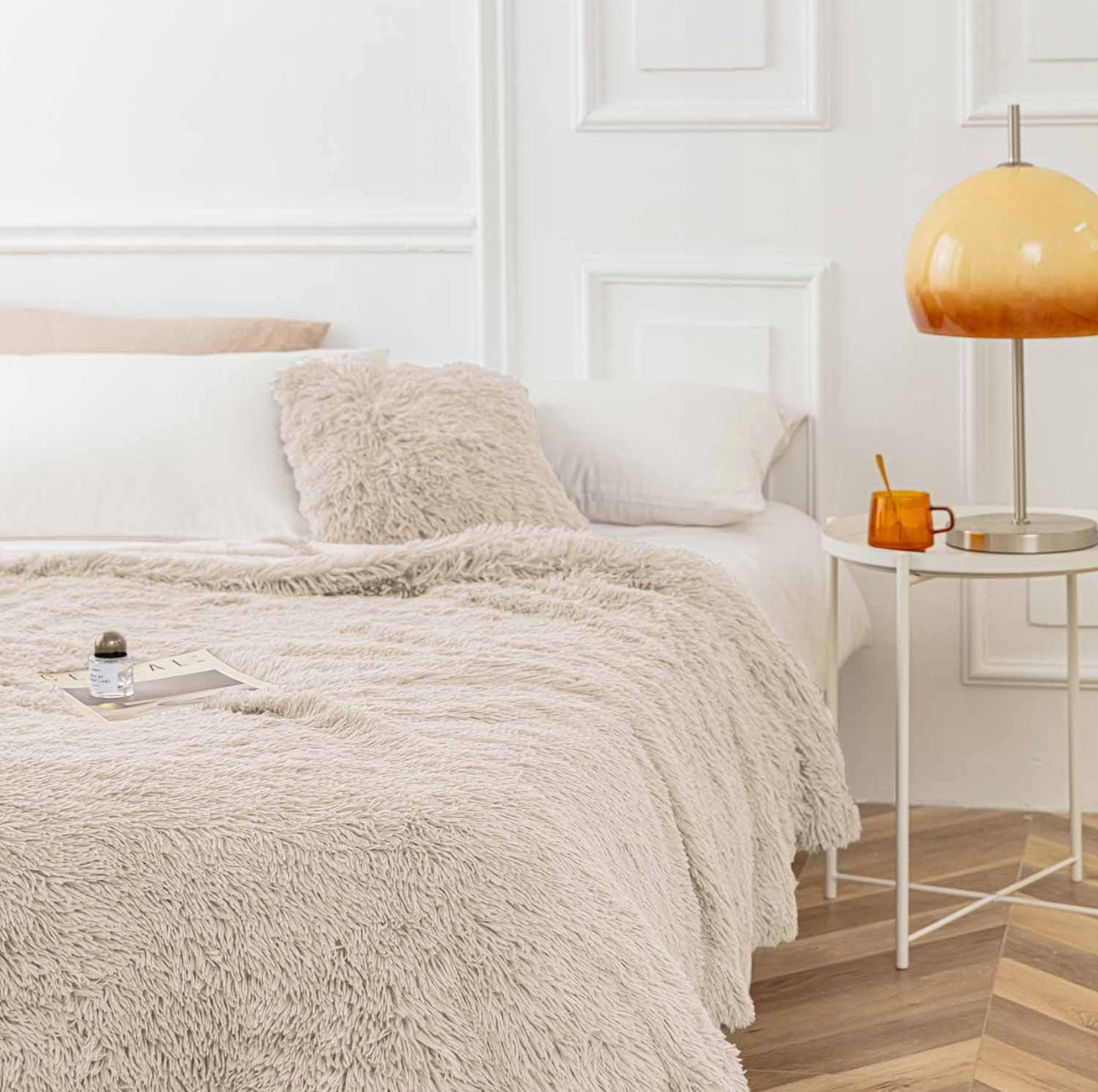 Beige fuskepelspledd elegant drapert over seng i lyst soverom