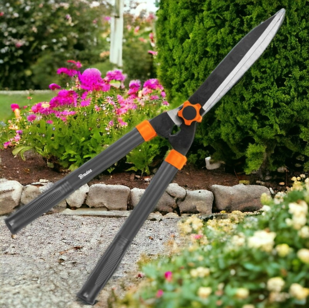 Hekksaks med lange håndtak og rette blader plassert i blomstrende hage