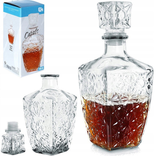 Elegant glasskaraffel med utskåret mønster og brun væske, stående ved siden av originalforpakning