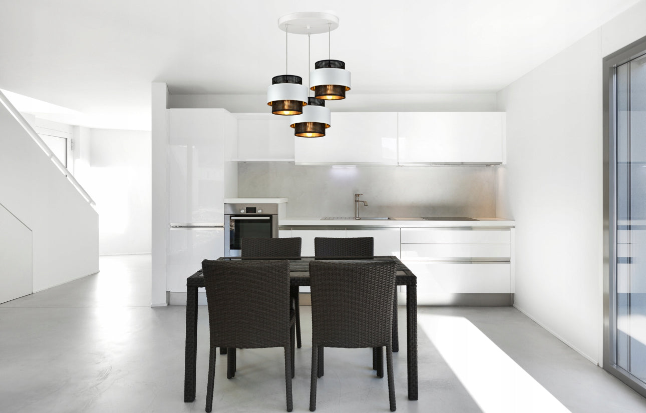 Elegant taklampe med fire skjermer over spisebord i minimalistisk hvit kjøkkeninnredning