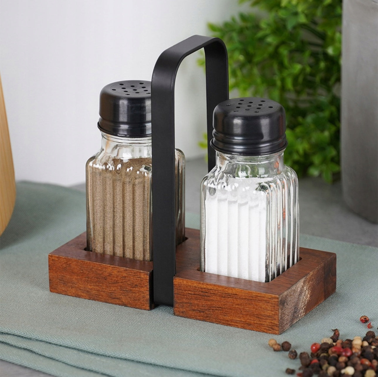 Elegant Salt- og Pepperbøssesett i Glass På Spisebord Dekorert Med Grønn Duk og Friske Urter