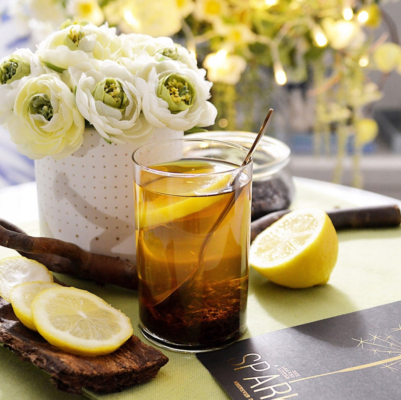 Glass med te og sitronskive på bord med blomster og dekor