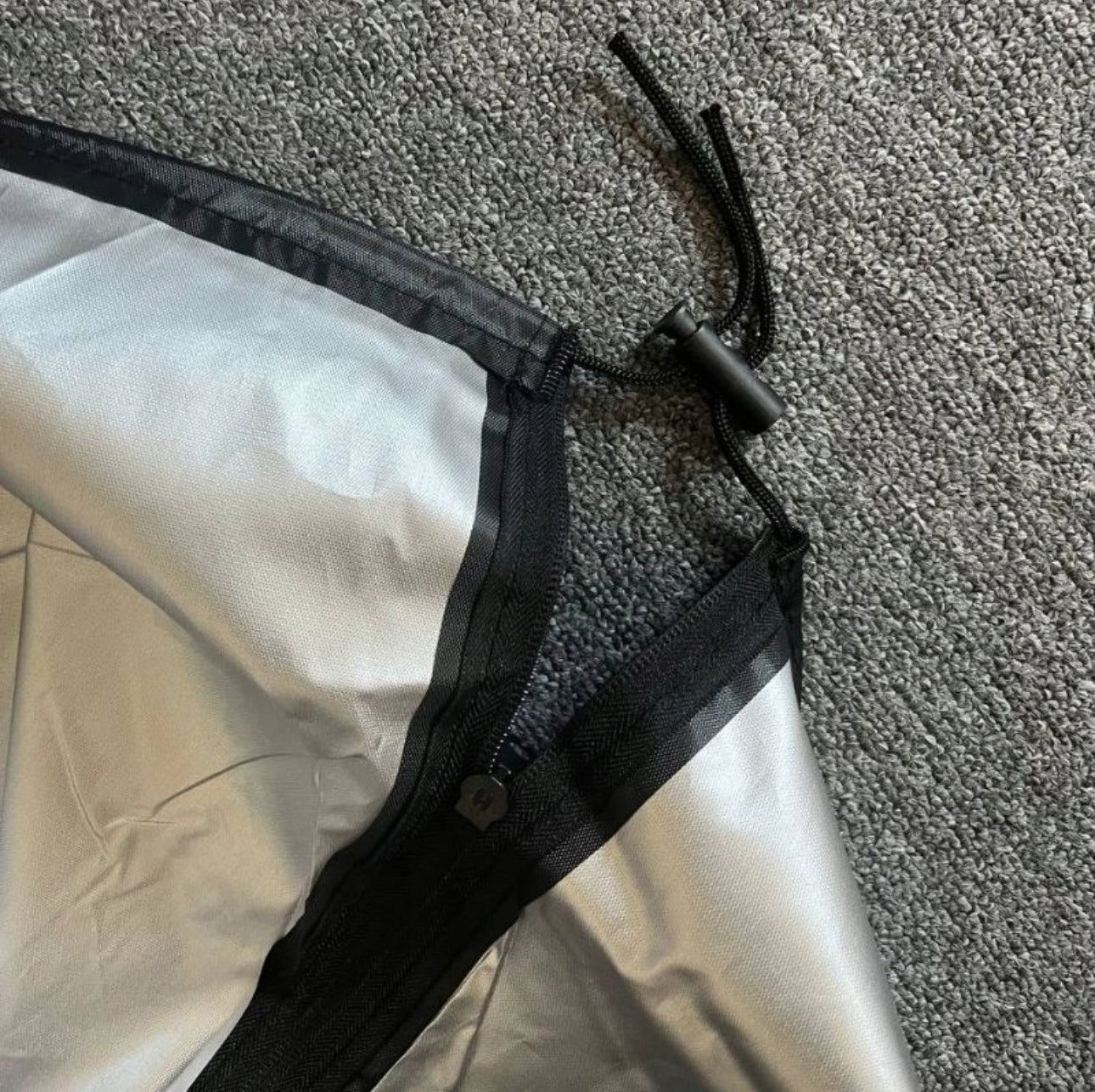 Detalj av glidelås og snorstramming på sort utendørs møbeltrekk