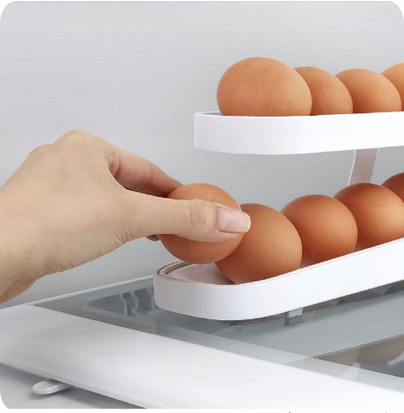 Hånd som tar egg fra hvitt stativ med skrå design i kjøleskap