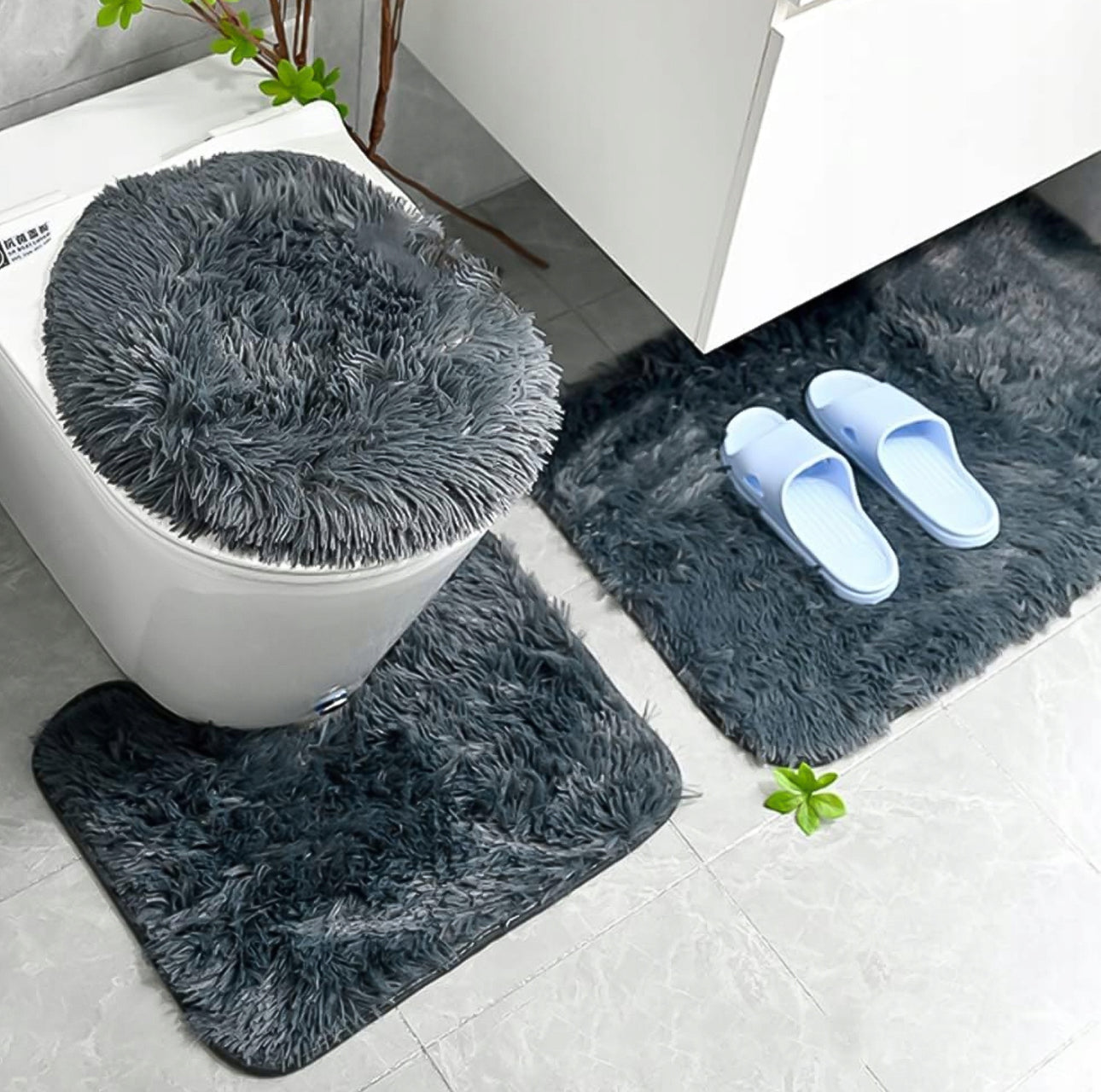 Grått 3-delt baderomsteppe med antiskli-funksjon – inkluderer teppe til badekar, toalettbase og toalettlokk. Laget av mykt og fluffy materiale for ekstra komfort og stil, perfekt for moderne baderomsdekor.