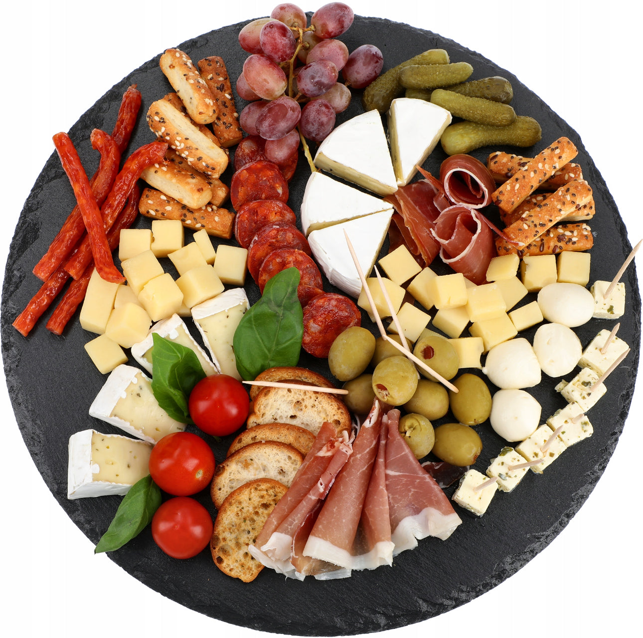 Ost- og tapasfat med spekemat, osteterninger, kjeks og grønnsaker på sort skiferplate