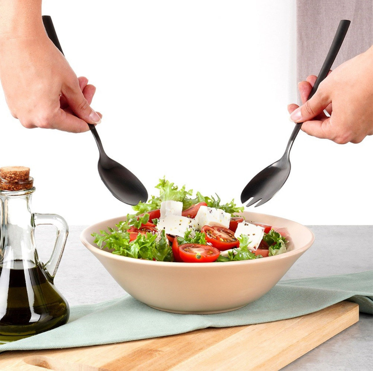 To hender som serverer salat med svarte bestikk over hvit bakgrunn