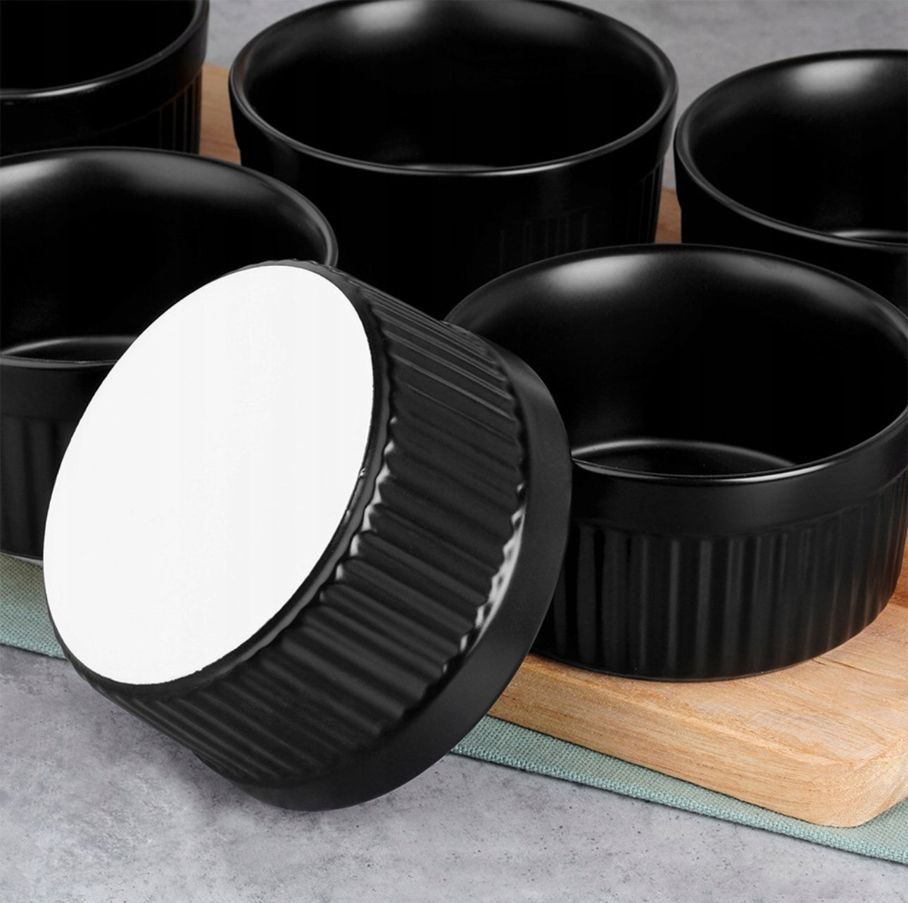 Nærbilde av svart keramikkform som ligger på siden, viser hvit bunn og rillet tekstur