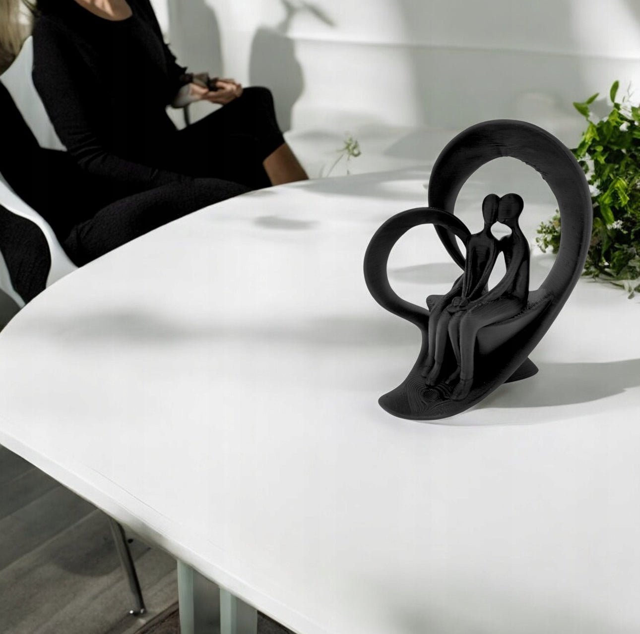 Dekorativ svart skulptur av par på hvit spisebordflate i moderne interiør