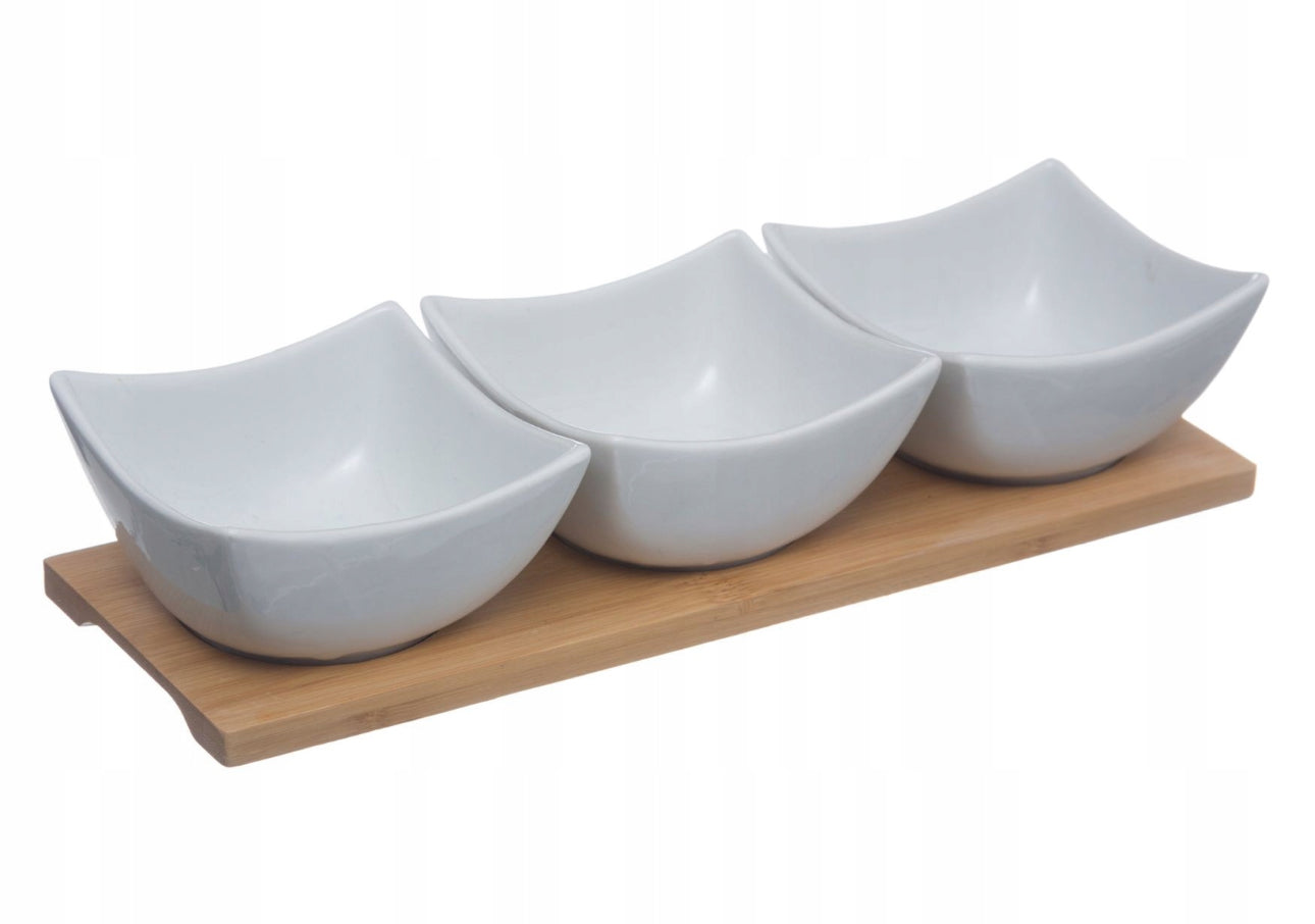 Serveringssett med tre hvite porselensskåler (9,7 x 9,7 x 5 cm) og en bambusbrett (30 x 10 cm) i elegant design. Perfekt for snacks, dips og sauser. Slitesterkt materiale og miljøvennlig. Hvitt og naturlig bambusfarget.