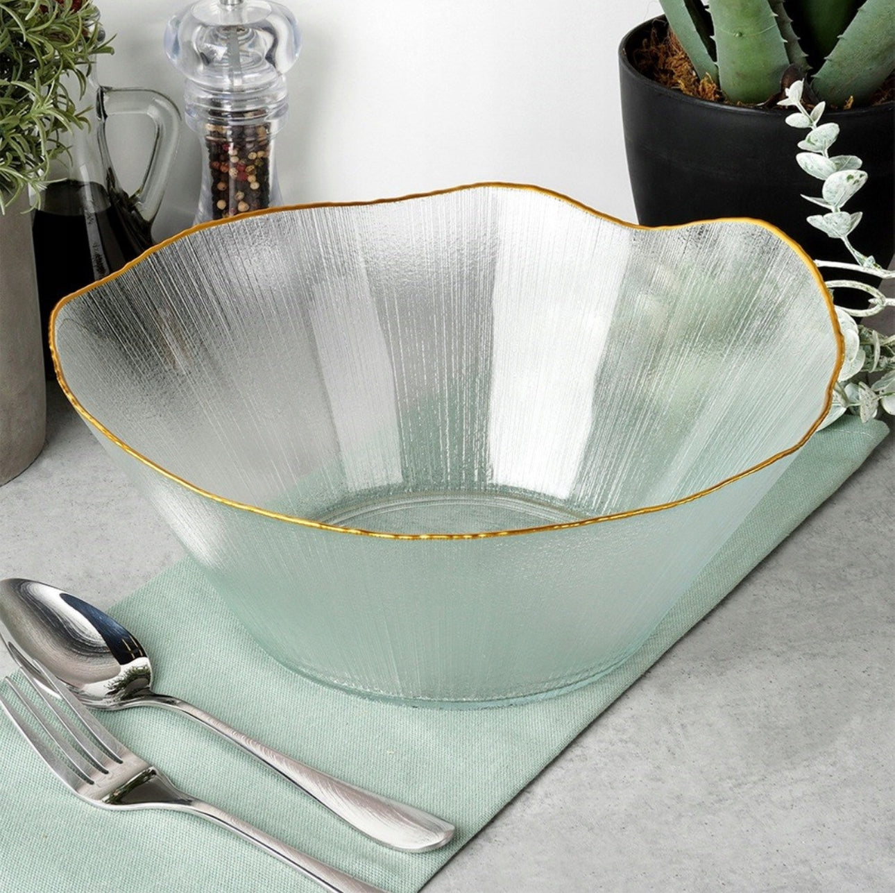 Moderne salatbolle i strukturert glass og gullkant, dandert med bestikk og grønne planter