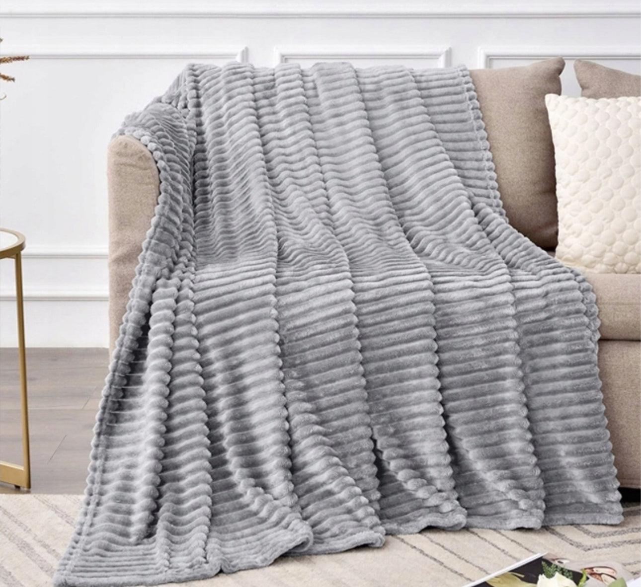 Lysgrått pledd med stripemønster drapert over sofa i stue