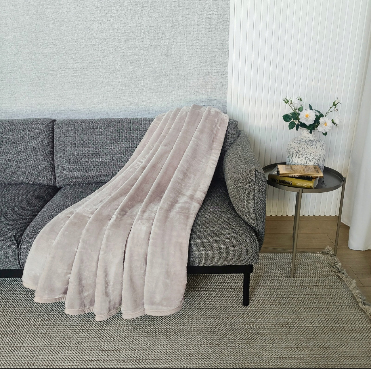 Grått pledd drapert over mørk grå sofa i minimalistisk stue