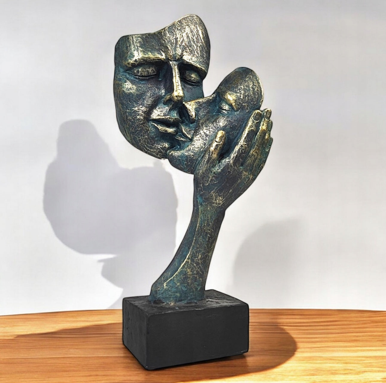 Elegant moderne skulptur av to ansikter i bronsefinish på trebord