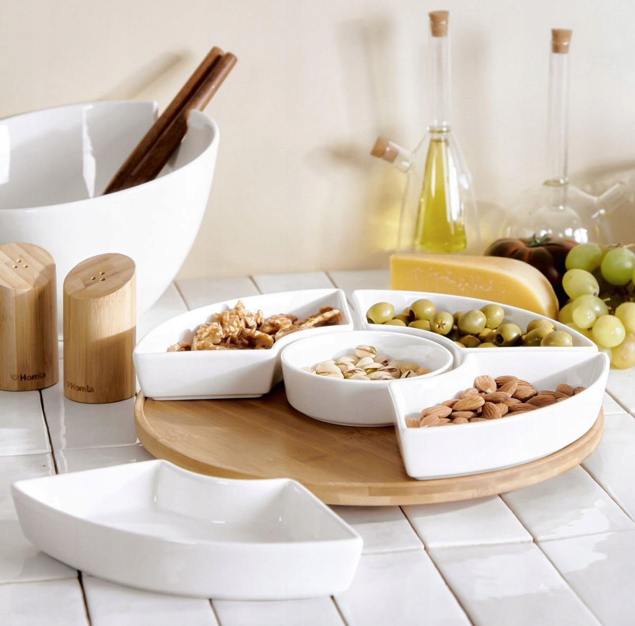 Elegant snacksett med nøtter og oliven i hvite skåler på kjøkkenbenk